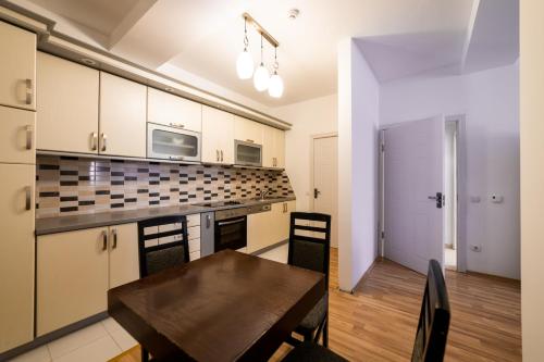 a kitchen with a wooden table and a dining room at CedarTREE Prishtina in Prishtinë