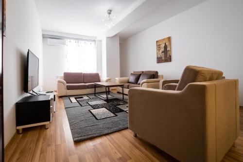 a living room with a couch and a tv at CedarTREE Prishtina in Prishtinë