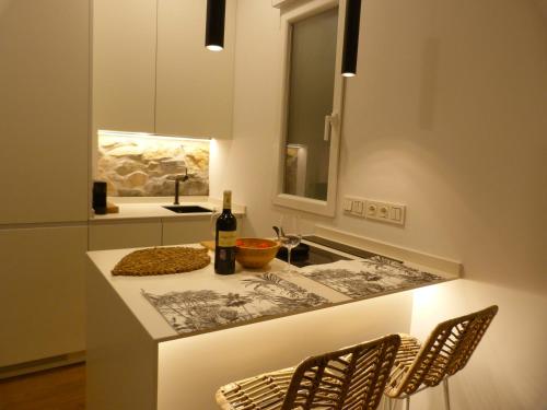 a kitchen with a counter with two chairs and a sink at Chic Gran Vía, nuevo apartamento de diseño en Gros by ChicDonosti in San Sebastián