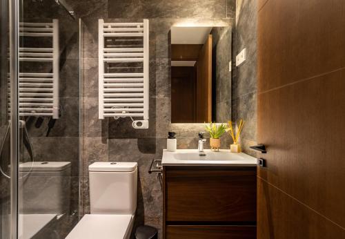 een badkamer met een wastafel, een toilet en een spiegel bij CERDANYA MOUNTAIN RESIDENCES in Bellver de Cerdanya 