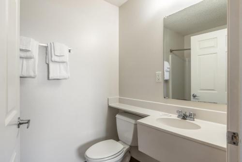 une salle de bain avec toilettes, lavabo et miroir dans l'établissement HomeTowne Studios & Suites by Red Roof Charlotte - Concord, à Concord