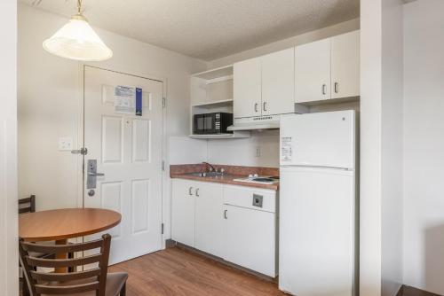 a kitchen with a table and a white refrigerator at HomeTowne Studios & Suites by Red Roof Charlotte - Concord in Concord