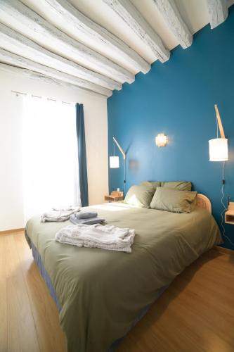 une chambre avec un grand lit avec un mur bleu dans l'établissement Le Mont Brenn, à Auxerre