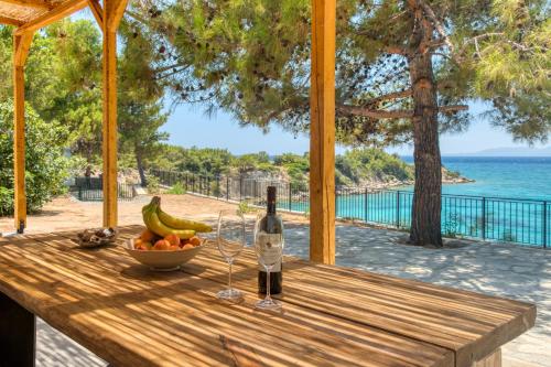 a bottle of wine and a bowl of fruit on a wooden table at Kavos beach house in Pefki Rhodes