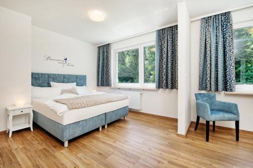 a bedroom with a bed and a chair and windows at Appartements Schwarzvilla in Velden am Wörthersee