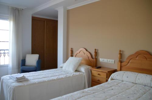 1 dormitorio con 2 camas y silla azul en Casa de Conde, en Coirón