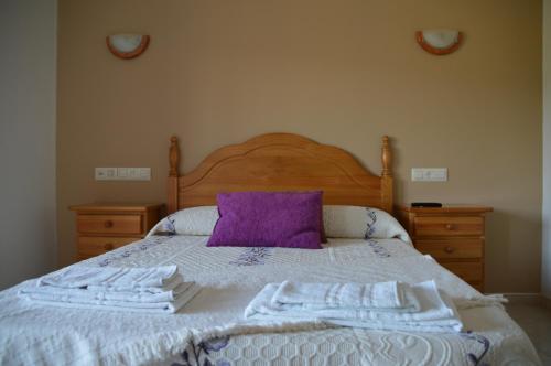 a bed with a purple pillow and white towels on it at Casa de Conde in Coirón