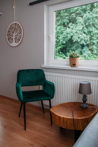 a green chair and a table in a room with a window at Szmaragdowy domek in Nowy Wiśnicz
