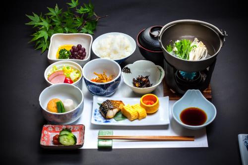 un tavolo con ciotole e piatti di cibo e bacchette di 료칸 여명 旅館 黎明 Ryokan Reimei a Yufu