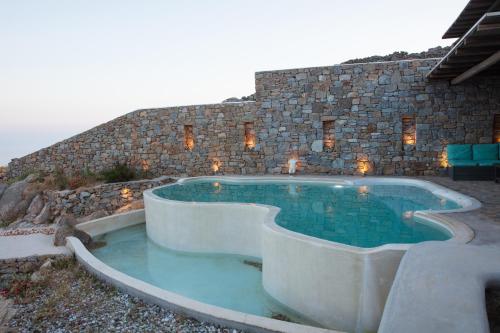 a swimming pool in front of a stone building at Amallini Suites Mykonos in Super Paradise Beach