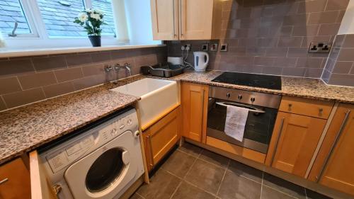 a kitchen with a washer and a sink and a stove at Spacious, bright and airy city centre flat. Unique converted Mill. in Manchester