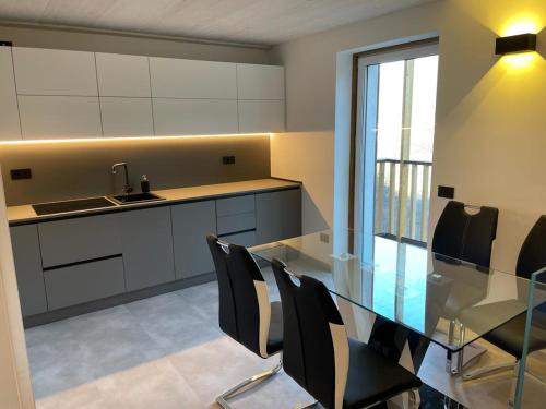 a kitchen with a glass table and black chairs at Graziosa, Casetta in Valgerola in Rasura