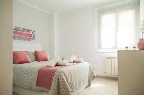 biała sypialnia z łóżkiem z różowymi poduszkami w obiekcie Toledo Enamora con Garaje w mieście Toledo