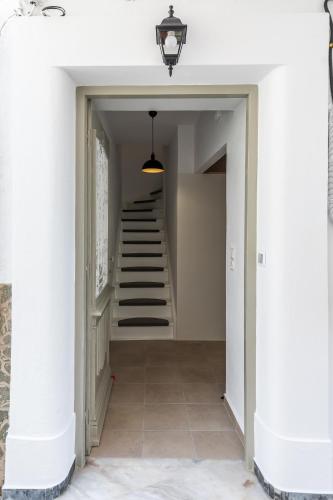 a hallway with white walls and stairs with a light fixture at Skopelitian Relaxing House in Skopelos Town