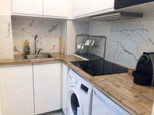 une cuisine avec un évier et une machine à laver dans l'établissement Appartement moderne & cosy au cœur de Paris, à Paris