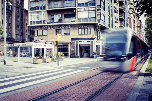 a train on a street in front of a building at Hotel Gran Via in Zaragoza