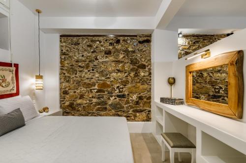 a bedroom with a stone wall and a white bed at Skopelitian Relaxing House in Skopelos Town