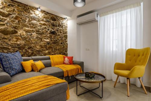 a living room with a couch and a stone wall at Skopelitian Relaxing House in Skopelos Town