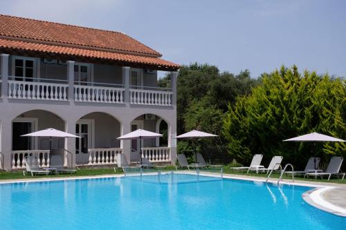 a swimming pool in front of a house with chairs and umbrellas at Katsaros Studios & Apartments in Sidari