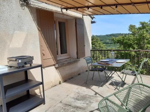 un patio avec une table et des chaises sur un balcon dans l'établissement La maison de Gaston au cœur du Luberon, à Villars