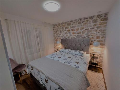 a bedroom with a bed and a brick wall at Apartman Zlatan in Drniš