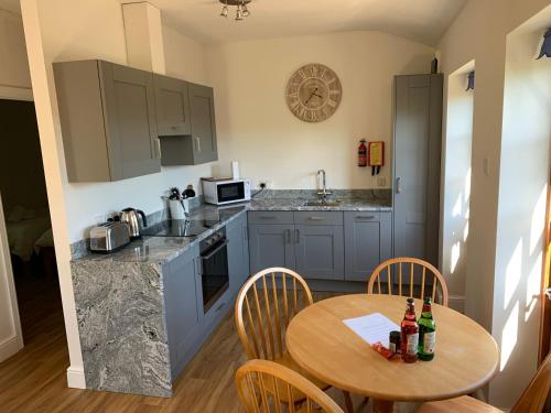 a kitchen with a wooden table and a small table with bottles on it at Ashton Cottages in Wedmore