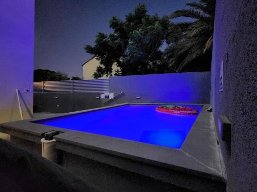 una piscina con iluminación azul en una casa en בית דירות - בית אורן, en Beit She'an