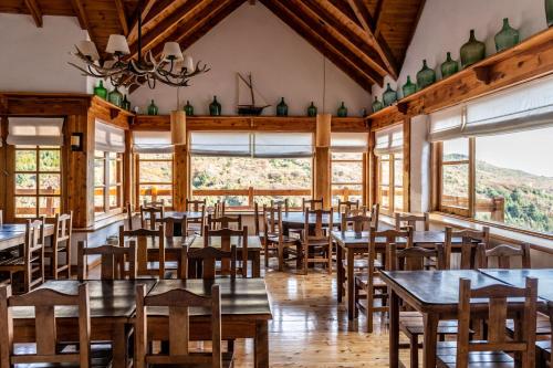 un comedor con mesas, sillas y ventanas en Hostería del Cerro en San Carlos de Bariloche