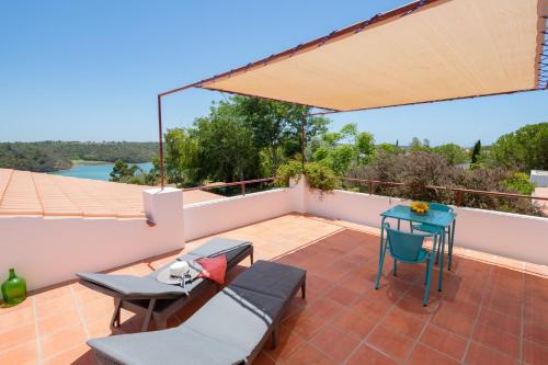 a patio with chairs and a table on a roof at Casa no Rio - River House in Vila Nova de Milfontes
