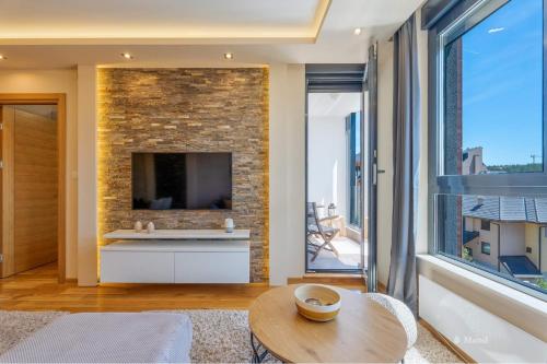 a living room with a brick wall and a large window at Mond Apartman in Zlatibor
