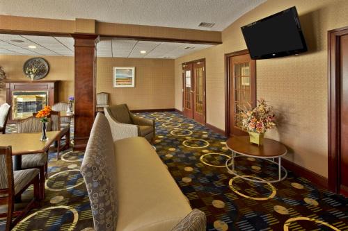 a hotel room with a couch and a flat screen tv at Holiday Inn Express Hotel & Suites Woodhaven by IHG in Woodhaven