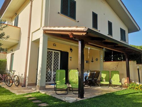 un patio con sedie verdi di fronte a una casa di Cactus 2020 a Sabaudia