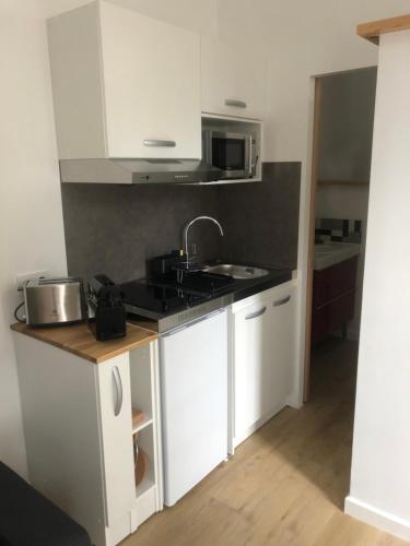 une cuisine avec des armoires blanches et un évier dans l'établissement Superbe studio centre ville La Rochelle, au calme, à La Rochelle