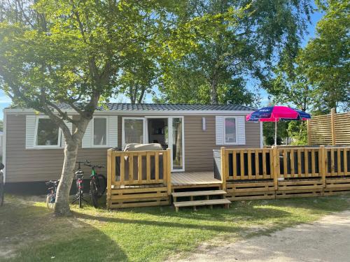 a mobile home with a deck with an umbrella at Chalet op Camping Lauwersoog met 3 slaapkamers en vaatwasser - JoyCasa in Lauwersoog