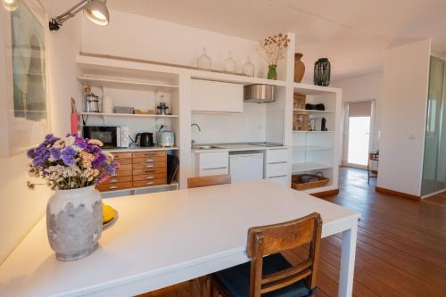 a kitchen with a table with a vase of flowers on it at Casa no Rio - River House in Vila Nova de Milfontes