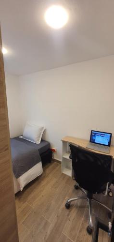 a bedroom with a bed and a desk with a laptop at Portal Norte 170 ACOGEDORAS HABITACIONES CON TODOS LOS SERVICIOS in Bogotá