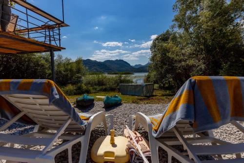 two lawn chairs sitting on a beach with a view of a lake at Lake House Buric in Vranjina