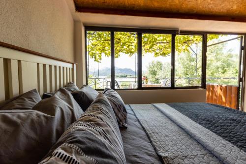 a bedroom with a large bed with a large window at Lake House Buric in Vranjina