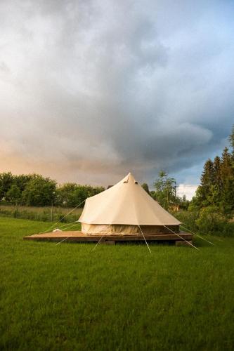 a canvas tent in a field with a cloudy sky at Stan u.nás in Dolní Řasnice