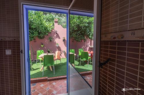 Une porte ouverte s'ouvre sur une terrasse dotée de chaises et de tables vertes. dans l'établissement villa Rita chaouen, à Chefchaouen