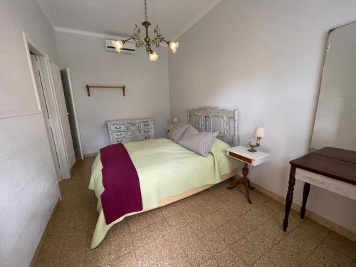 a bedroom with a bed and a table and a chandelier at Chacras de Azcona Hostería in Azul