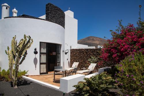 un patio con 2 sillas, una mesa y algunas flores en 5 Suites Lanzarote, en Mácher