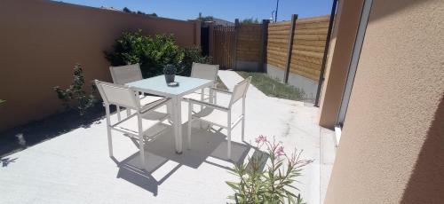 una mesa blanca y sillas en un patio en La Petite Maison du Bassin d'Arcachon - 40 m2, climatisée, indépendante et au calme en Audenge