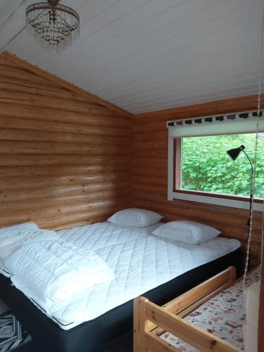 a bed in a room with a window at Hirsimökki ja makuuaitta in Karijoki