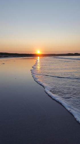 a sunset on a beach with the tide coming in at Eco Indigo in Dunbar