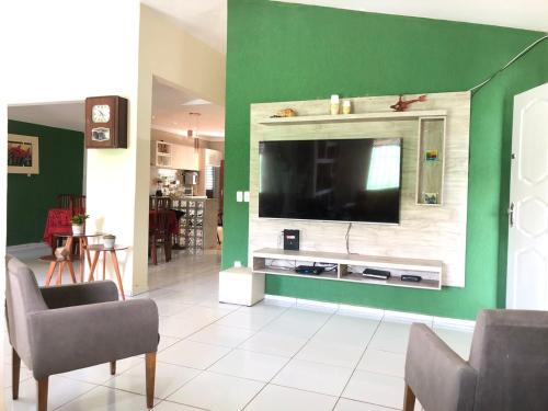 a living room with a television on a green wall at Casa ampla e aconchegante no coração de Ponta Negra in Natal