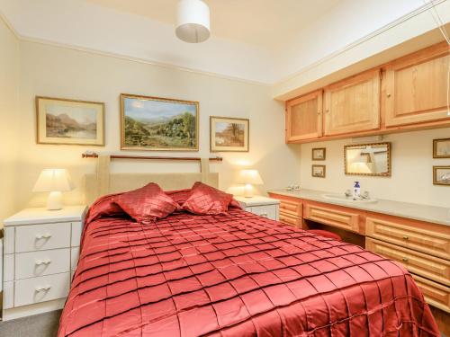 a bedroom with a bed with a red comforter at Clooneavin Apartment 5 in Lynmouth