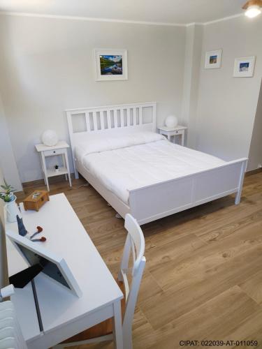 a white bedroom with a white bed and a desk at Pordoi H10 - with SAUNA in Alba di Canazei