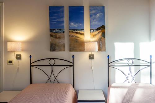 a bedroom with two beds and two paintings on the wall at CASE&COLLINE Villa Grazia in Montescudaio