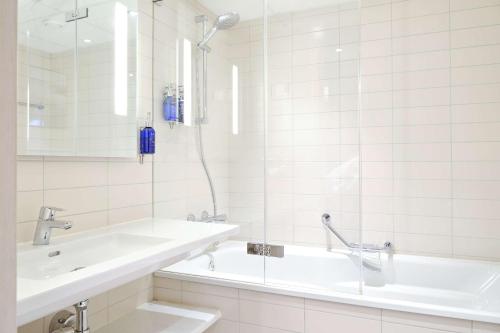 uma casa de banho branca com uma banheira e um lavatório em Radisson Blu Royal Garden Hotel, Trondheim em Trondheim